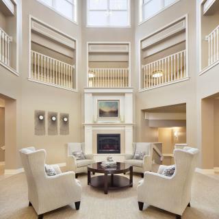 Elegant living room with armchairs surrounding a central fireplace and an open balcony design.