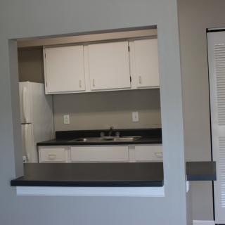 A modern kitchen with white cabinets and a counter overlooking a living area.