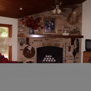 A cozy living room with a brick fireplace and various decorations on the mantel.