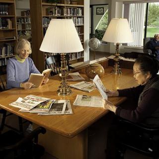 Two people reading at a table in a library.