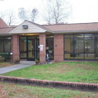 A small brick building with a glass entrance and surrounding windows.
