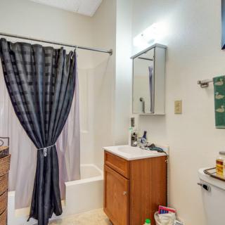 A small bathroom featuring a shower with a dark curtain, a vanity with a sink and mirror, and a toilet.