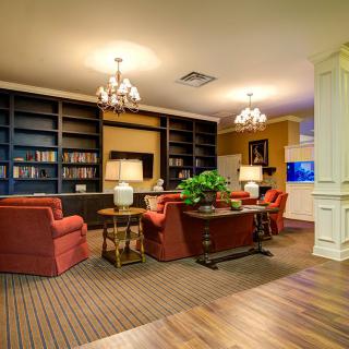 A cozy library interior with armchairs, bookshelves, and chandeliers.