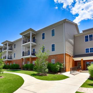 A modern apartment building with well-maintained landscaping on a sunny day.