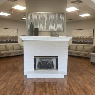 A modern lobby featuring a central fireplace, surrounded by sofas and contemporary artwork.