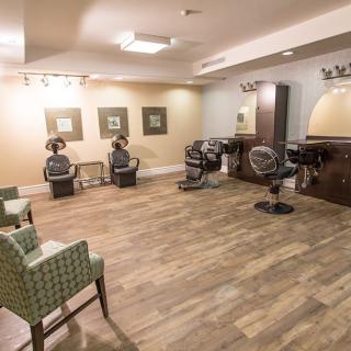 A cozy hair salon interior with wooden flooring, featuring chairs, mirrors, and hairdryers.