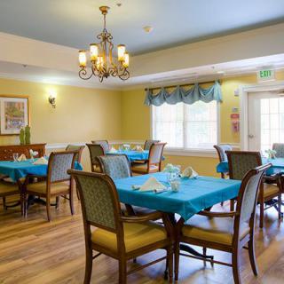 A well-lit dining room with several tables and chairs, featuring elegant decor and a chandelier.