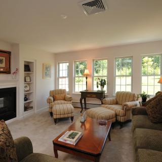 A cozy living room with comfortable seating, large windows, and a fireplace.