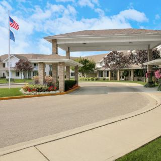 A scenic view of a residential building entrance with a driveway and flag.