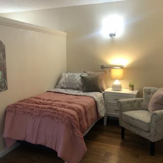 A cozy bedroom with a single bed, warm lighting, and comfortable seating.