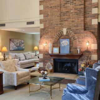 A cozy living room with a central brick fireplace surrounded by comfortable seating and elegant decor.