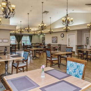 A spacious dining hall with elegant chandeliers and neatly arranged tables and chairs.