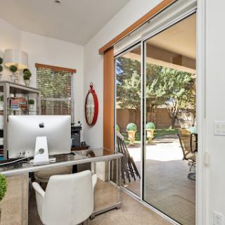 A bright and modern home office featuring a sleek desk, computer, and large glass doors leading to an outdoor space.