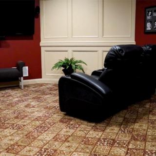 A cozy living room with recliner seating, a TV on the wall, and decorative plants on patterned carpet.