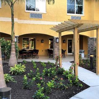A landscaped patio area with outdoor seating and a pergola in front of a building.