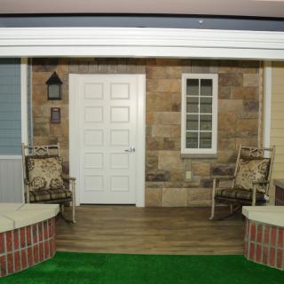A cozy patio setup with a white door, two chairs, and surrounding brick walls.