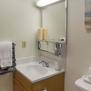 A small bathroom with a sink, mirror, and neatly arranged towels.