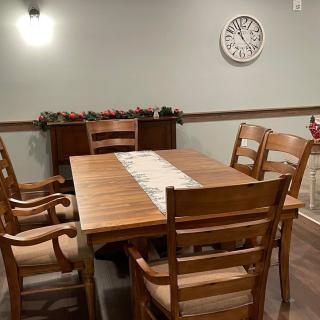 A cozy dining room with wooden furniture and a decorative wall clock.