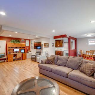 A spacious and modern living room with a cozy sofa, wooden flooring, and an adjacent dining area.