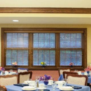 A well-decorated dining room with wooden blinds and neatly set tables.
