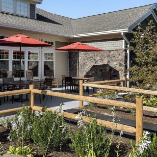 A cozy patio area with red umbrellas and outdoor seating, surrounded by a small garden.
