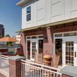 A cozy outdoor patio with wooden furniture and an umbrella on a sunny day.