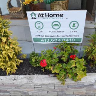 A garden sign promoting home services, surrounded by vibrant flowers.