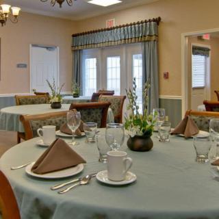An elegantly set dining room with neatly arranged tables and chairs, featuring fine tableware and tasteful decor.