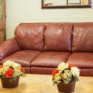 A brown leather sofa with floral arrangements on the table in a cozy living room.