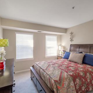 A cozy bedroom with a large bed, two windows, and stylish decor.