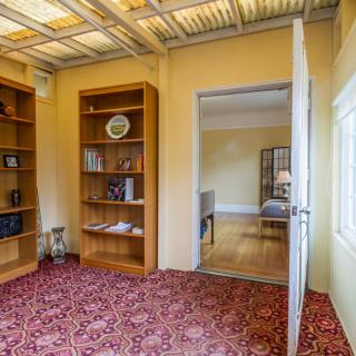 A cozy room with an open door, featuring bookshelves and a red patterned carpet.