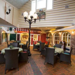 A cozy restaurant interior with a charming dining area, featuring neatly arranged tables and chairs under warm lighting.