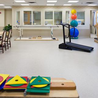 A rehabilitation room with exercise equipment, including a treadmill and therapy balls.