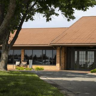 A building with a brown roof and large windows surrounded by trees.