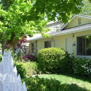 A cozy house with a white picket fence and lush greenery.