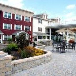 A modern building with an outdoor patio area featuring chairs and tables.