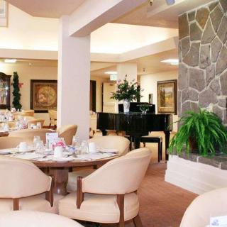 A cozy restaurant interior featuring elegant dining tables, comfortable chairs, and a grand piano.
