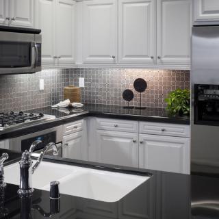 A modern kitchen with white cabinets, stainless steel appliances, and a sleek black countertop.