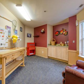 A cozy craft room with a work table, chair, and colorful decorations.