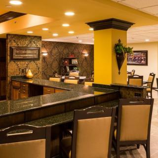 A stylish restaurant interior featuring a bar with seating and warm lighting.
