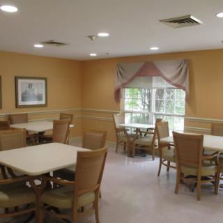 A cozy dining room with multiple tables and chairs, featuring a window with drapes.