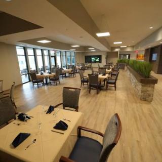 A modern, spacious restaurant dining area with neatly arranged tables and chairs.