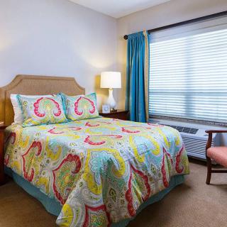 A cozy bedroom with colorful bedding and natural light streaming through the window.