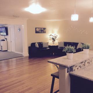 A modern living area with a cozy sofa, hardwood floors, and an open kitchen counter space.