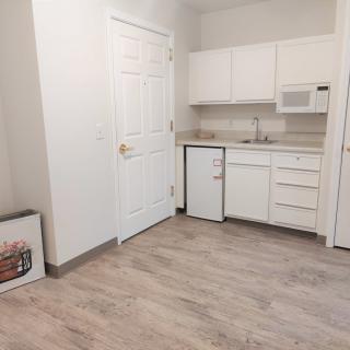 A minimalist kitchen featuring white cabinets and wooden flooring.