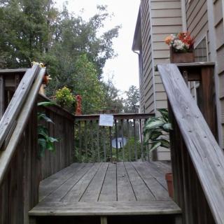 A wooden deck with stairs leading to a house, adorned with plants and flowers.