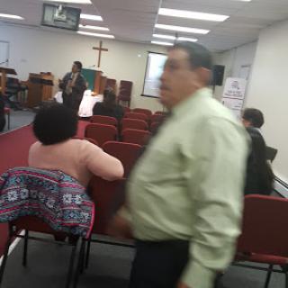 A gathering inside a church with attendees seated and someone walking past.