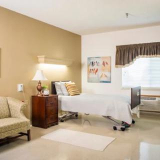 A well-furnished hospital room with a patient bed, sofa, and window.