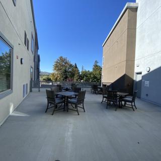 An outdoor patio area with tables and chairs between two buildings on a clear day.