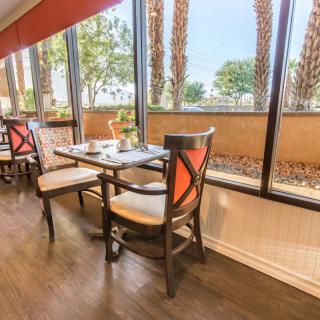 A cozy restaurant dining area with tables and chairs next to large windows, offering a bright and inviting atmosphere.